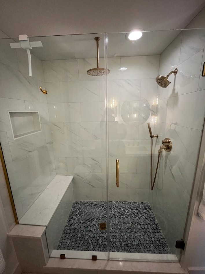 Light-filled bathroom with a freestanding tub, long white vanity, decorative mirrors, and a shaded window.